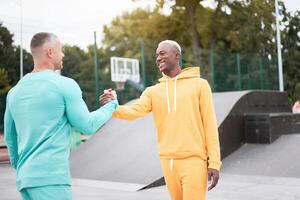 Multi-ethnic friendship Black african-american and caucasian guy friends spending time together on skate park photo