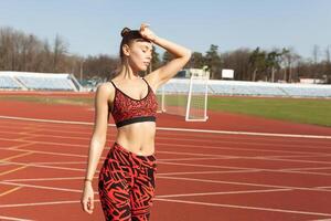 hermosa caucásico niña atleta descansando después trotar en un corriendo pista. foto