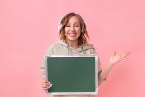 Woman holding empty chalkboard over pink background photo