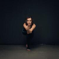 Woman practicing yoga against a dark texturized wall photo