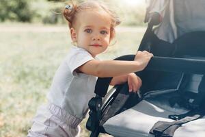 Baby girl standing near a baby carriage photo