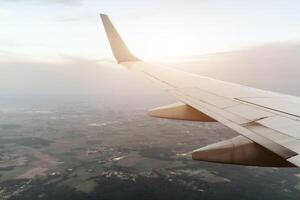 The wings of the airplane are above the clear sky at sunset. photo