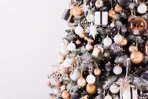 Christmas tree close up standing white wall background decorated white black gold color with light garland photo