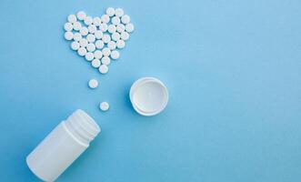 medicine, healthcare and pharmacy concept - pills and of drugs in shape of the heart photo