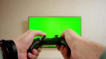 Man gamer hands holding modern console for play station close-up, guy playing video games. Shooting of male arms with remote controller. Professional cybersport. Green screen, chroma key