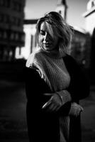 Confident Woman in Sweater Stands with Arms Crossed in Front of Building. Stylish Female Portrait. Urban Lifestyle Concept with Fashionable Woman in City Setting photo
