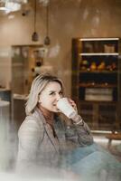 acogedor café momento. mujer disfrutando café en elegante atuendo - relajante café ambiente con mujer en chaqueta y bufanda saboreando café - casual café descanso en cómodo café ajuste foto