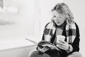 acogedor café momento. mujer disfrutando Moda revista y café - relajación y recreación en café ajuste - sin prisa leyendo y bebiendo café en acogedor café ambiente, estilo de vida concepto foto