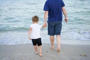 Father son spending time together sea vacation Young dad child little boy walking beach photo