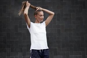 Woman Ties her hair in a ponytail before morning workout black wall background photo