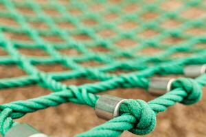 Rope mesh with blurry background. It is a green rope mesh in a playground. It is not a brand new rope mesh but it is old and deteriorate. photo