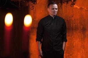 Portrait of handsome catholic priest or pastor with dog collar, dark red background. photo