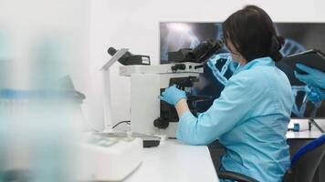 médico pesquisa cientista parece às biológico amostras debaixo digital microscópio dentro aplicado Ciência laboratório. lindo caucasiano laboratório engenheiro dentro branco casaco trabalhando em vacina e remédio video