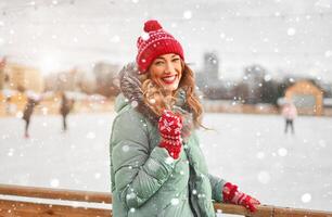 Beautiful lovely middle-aged girl with curly hair warm winter jackets stands ice rink background Town Square. photo