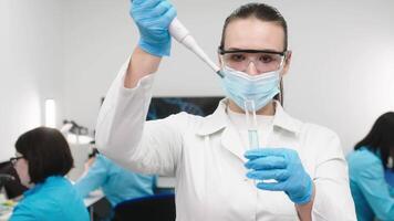 medisch Onderzoek laboratorium. een wetenschapper werken met een pipet en een test buis. wetenschappelijk laboratorium van biotechnologie, ontwikkeling van geneeskunde en Onderzoek in chemie, biochemie en experimenten video