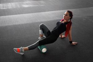 Woman massaging foam roll leg gym myofascial release exercise rolling, trigger points photo