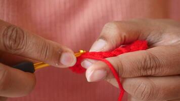 Hand close up crocheting with a pink hook, wool yarn, creative craft video