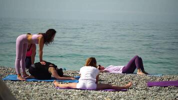 Young woman with black hair, fitness instructor in leggings and tops doing stretching and pilates on yoga mat near the sea. Female fitness yoga routine concept Healthy lifestyle harmony and meditation video