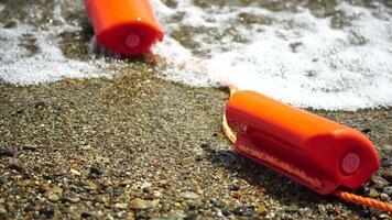 Orange safety buoys on a rope floating in the sea on a sunny day, close up. Fencing of the swimming area on the beach. video