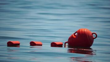 naranja la seguridad boyas en un cuerda flotante en el mar en un soleado día, cerca arriba. Esgrima de el nadando zona en el playa. video