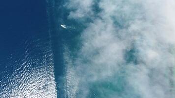 aereo barca gara. lusso crociera viaggio su blu mare con nebbioso nuvole a soleggiato giorno. veloce barca con bianca impronte su acqua superficie. paesaggio marino a partire dal drone. vacanza, vacanza e viaggio. video