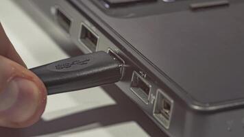 Close up of hand inserting plugging data cable into usb port in laptop 2 video