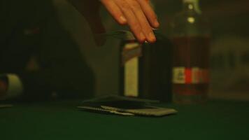 Mans hands reach out to pick up a stack of poker cards from a table in nightclub video