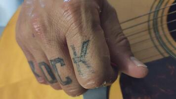 Hand with rock tattoo plays guitar video