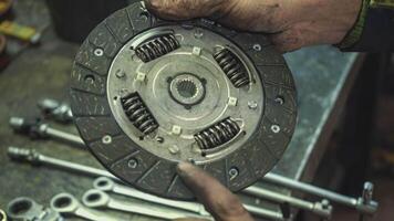 A car mechanic is showing an old car clutch disk video