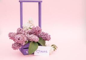 Beautiful bouquet of purple lilac and card on purple paper background photo