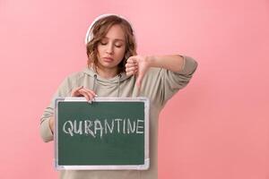 Stay home concept Woman with headphones dressed oversize hoodie holds chalkboard with the words quarantine photo