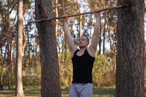 Handsome caucasian men pull-up outdoor workout cross training morning Pumping up arm exercising sports ground nature forest photo