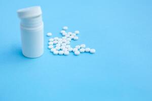 Pills and pill bottle on blue paper background photo