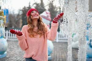 Beautiful lovely middle-aged girl with curly hair warm winter sweater stands ice rink background Town Square. photo