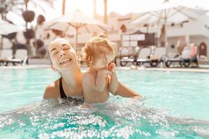 Mom and little daughter are played in the open swimming pool. Family with one child on vacation in warm countries. Positive people on vacation. photo