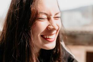 Happy young smiling woman with freckles outdoors portrait. Soft sunny colors. Outdoor close-up portrait of a young brunette woman and looking to the camera, posing against autumn nature background photo