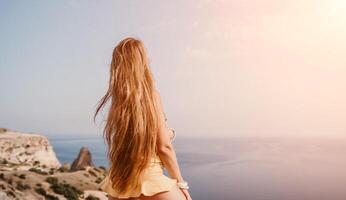 mujer viaje mar. contento turista tomando imagen al aire libre para recuerdos. mujer viajero mira a el borde de el acantilado en el mar bahía de montañas, compartiendo viaje aventuras viaje foto