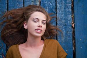 Beautiful caucasian young woman Lying on her back on wooden background. photo