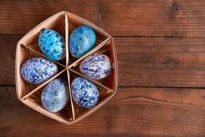 Blue cosmos chicken eggs lie in round wooden basket which stands on a dark wooden table. photo