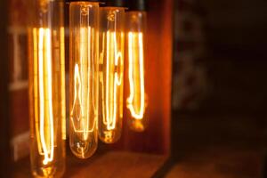 Light bulb lamp on dark red brick background with hotspot close up loft photo