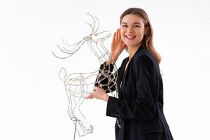 Young business woman holding illuminated Christmas deer decor dressed black suit isolated on white background photo