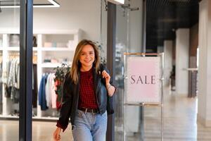 Young beautiful girl goes out clothing store with purchases. Season sale happy young adult female photo