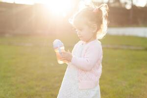 soft focus photo of little curly girl with two tails walking in the backyard on the green grass