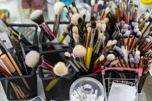 maquillaje cepillos allí un lote de cepillos al azar en pie en contenedores a el lugar de trabajo de un maquillaje artista o estilista. foto