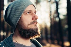 un joven hombre con un barba camina en un pino bosque. retrato de un brutal barbado hombre otoño bosque foto