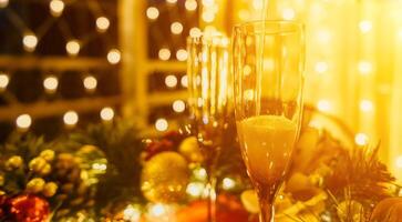 Two champagne glasses filled with champagne are placed on a table with a fruit arrangement. The glasses are surrounded by lights, creating a festive atmosphere. photo