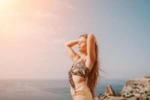 Woman travel sea. Happy tourist taking picture outdoors for memories. Woman traveler looks at the edge of the cliff on the sea bay of mountains, sharing travel adventure journey photo