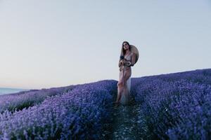 Woman lavender field. Happy carefree woman in beige dress and hat with large brim smelling a blooming lavender on sunset. Perfect for inspirational and warm concepts in travel and wanderlust. Close up photo