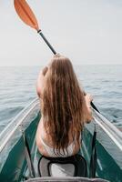 Woman in kayak back view. Happy young woman with long hair floating in transparent kayak on the crystal clear sea. Summer holiday vacation and cheerful female people relaxing having fun on the boat photo