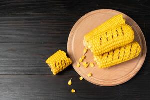 Grilled hot Corn cob lies on cutting board wooden table background. photo